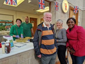 A photo showing five volunteers leaning on the kitchen counter and smiling.